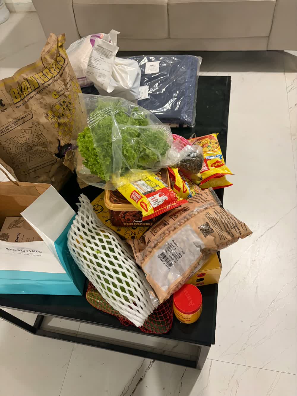 Groceries from the order piled loose on a table with no delivery bag